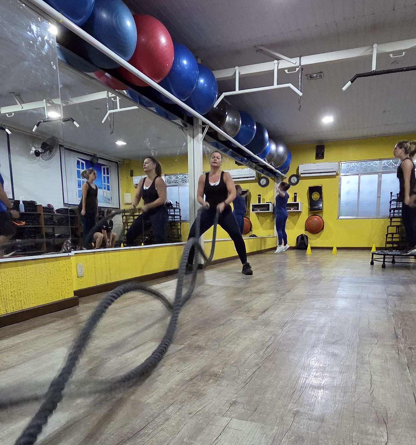 Alunos realizando aula coletiva de HIIT com acompanhamento de professor.