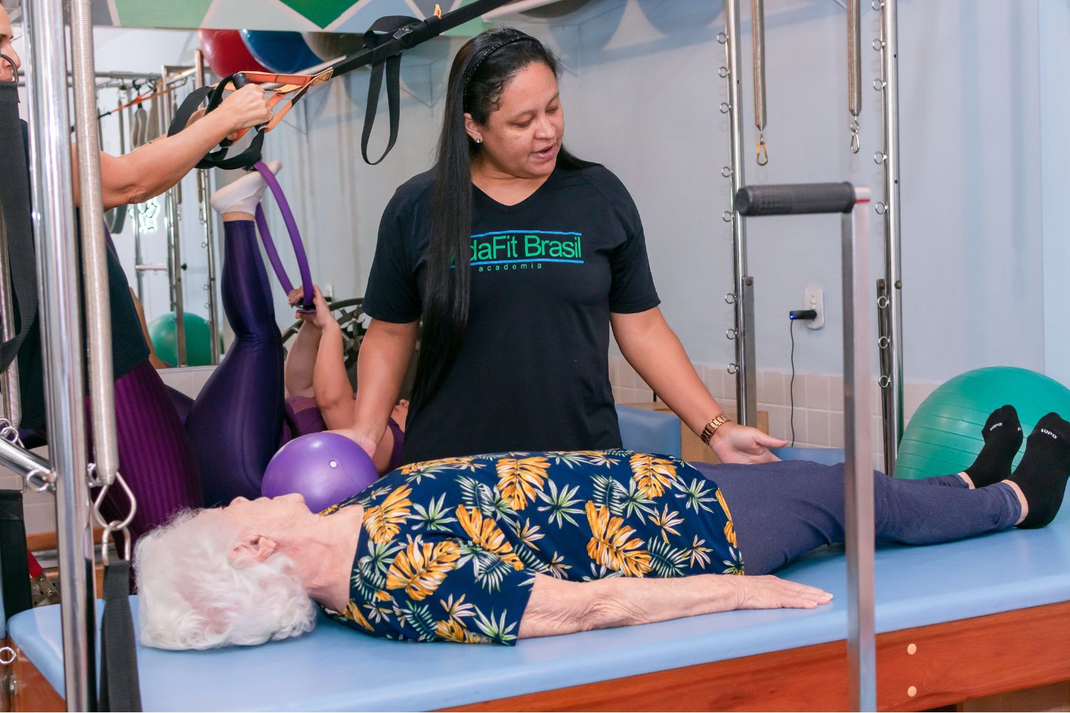 Fisioterapeuta acompanhando aluna durante aula de Pilates.